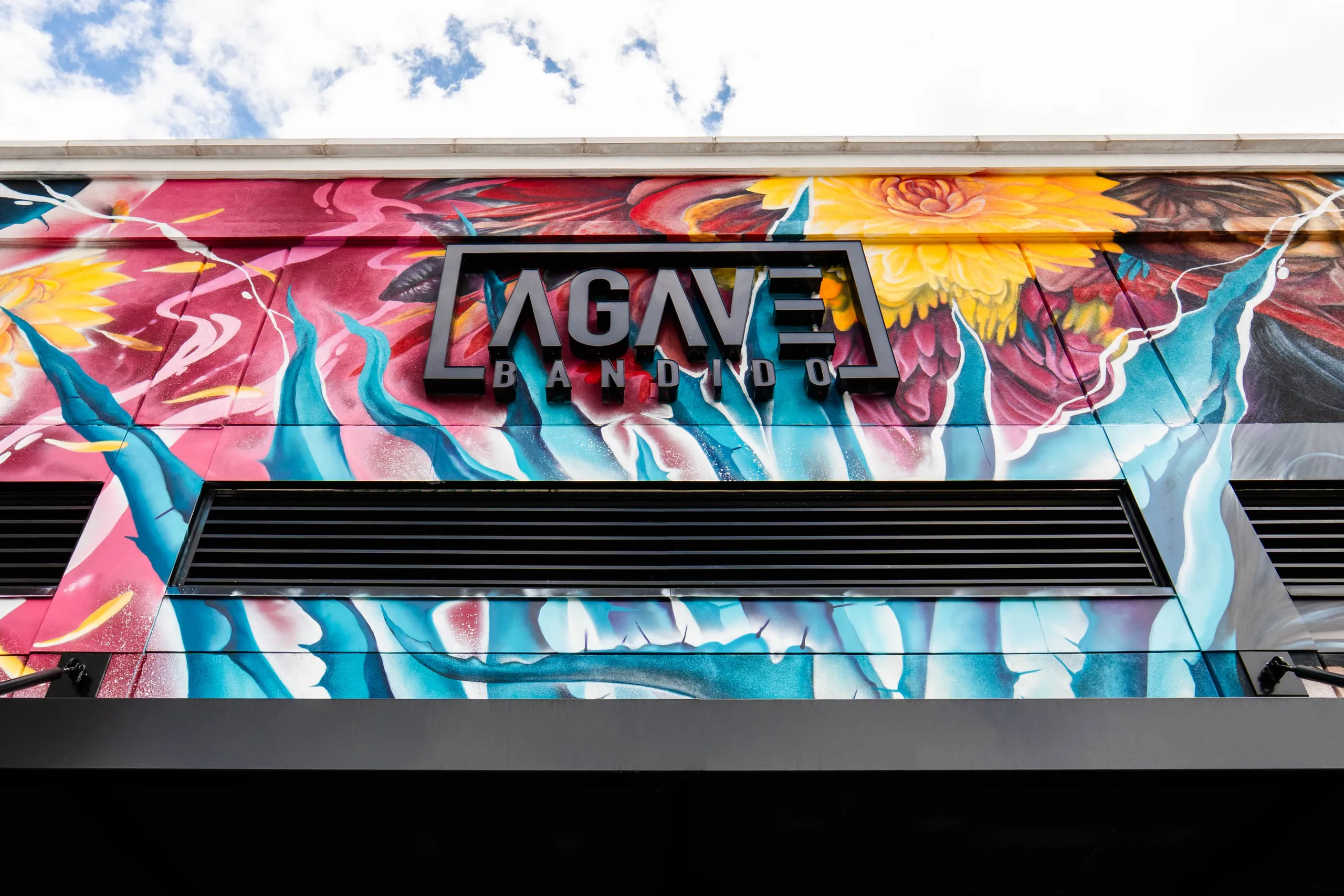 The Agave Bandido sign on the painted mural wall of the restaurant