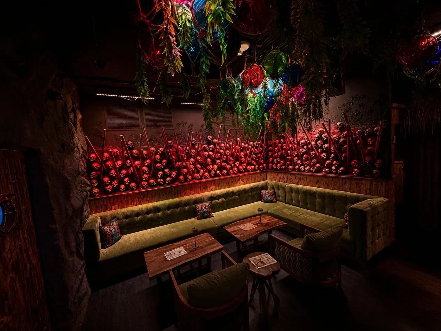 The wall of skulls lit in red above the green banquette at Maya